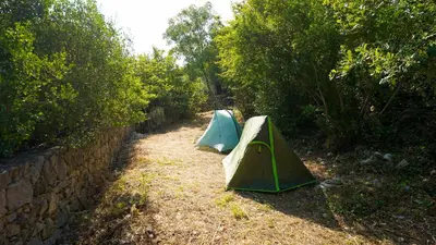 two tents in a field next to a wall at Montenegro Tower in Pečurice