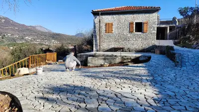 a person walking in front of a stone house at Montenegro Tower in Pečurice