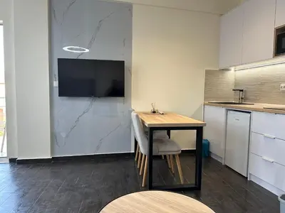 a kitchen with a table and a tv on a wall at Apartment Angela in Donji Štoj