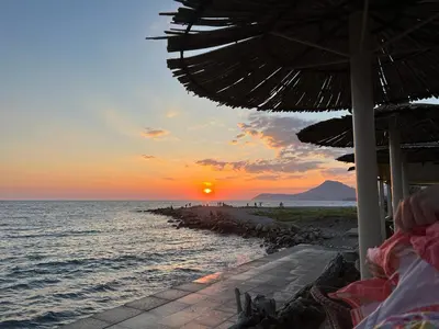 a sunset on a beach with an umbrella and the ocean at Sea in Bar