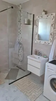 a bathroom with a shower and a sink and a washing machine at Apartment Kata in Cetinje