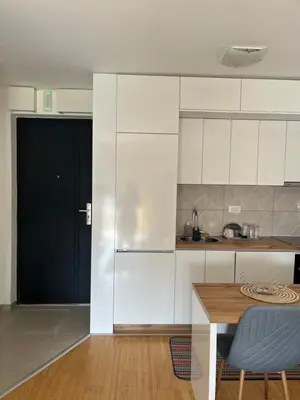 a kitchen with white cabinets and a wooden table at Marelica Apartman in Bar