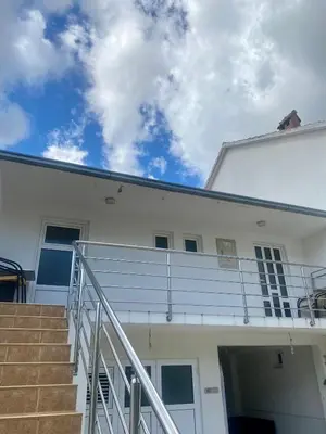 a white building with stairs and a cloudy sky at Apartment Maša in Radanovići