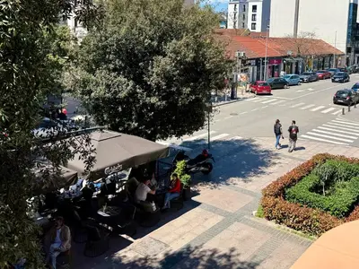 a group of people sitting under a tent on a city street at Center Square in Podgorica