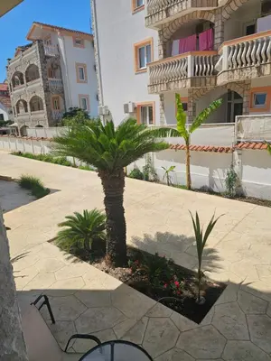a palm tree in a courtyard in front of a building at La Vida Apartments in Babalonija