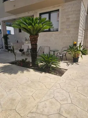 a patio with chairs and a palm tree in front of a building at La Vida Apartments in Babalonija