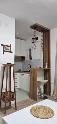 a kitchen with white cabinets and a wooden desk at Apartman Olivera in Sutomore