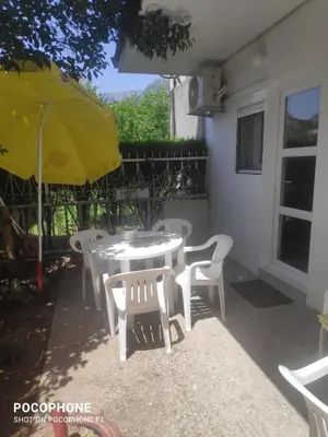 a white table and chairs with a yellow umbrella at Apartman Olivera in Sutomore