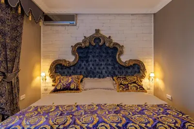 a bedroom with a large bed with a blue and gold headboard at VILLA-BAROCCO Sveti-Stefan & Private Garden in Sveti Stefan