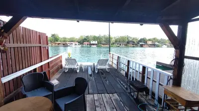 a boat with chairs on a dock on the water at Sidro river house in Ulcinj