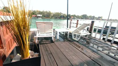 three chairs and a table on a dock near the water at Sidro river house in Ulcinj