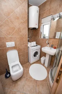 a bathroom with a toilet a sink and a washing machine at Sky Center Apartment in Podgorica