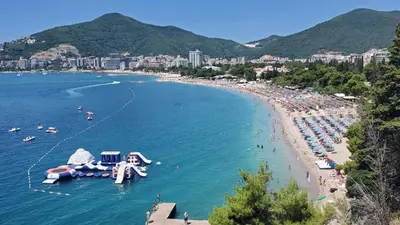 a beach with a bunch of people in the water at Status-M Apartments Rozino in Budva
