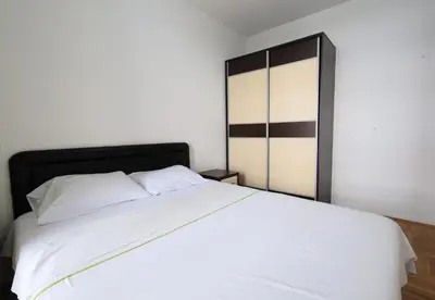 a bedroom with a white bed with a black headboard at Status-M Apartments Rozino in Budva