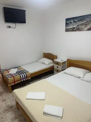 a room with two beds and a flat screen tv at Apartmani Resetar 2 in Brca