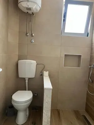 a bathroom with a toilet and a window at Apartments Drini in Ulcinj