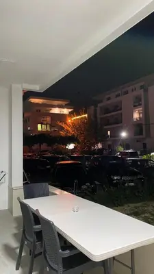 a white table and chairs with a view of a parking lot at Apartments Drini in Ulcinj