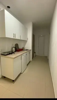 a kitchen with white cabinets and a white floor at Apartments Drini in Ulcinj