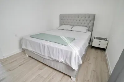 a bedroom with a bed with white sheets and a night stand at Apartman Skadarsko jezero bay in Vranjina