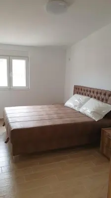 a large bed in a white room with two windows at Liona in Sutomore