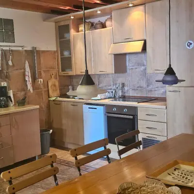 a kitchen with wooden cabinets and a table and chairs at Stonehouse Mimi in Lapčići