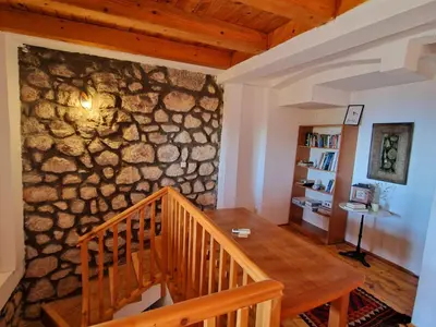 a room with a wooden table and a stone wall at Stonehouse Mimi in Lapčići