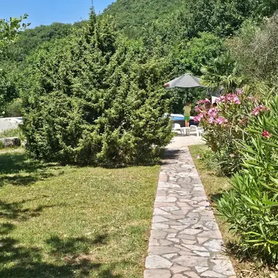 a garden with a stone path and flowers and an umbrella at Stonehouse Mimi in Lapčići