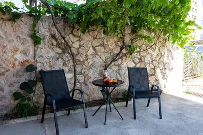two chairs and a table in front of a stone wall at Shanti apartments in Bar