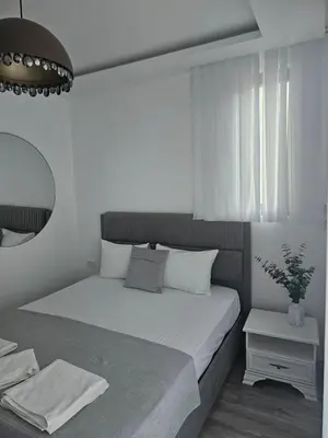 a white bedroom with a bed and a mirror at La Vida Apartments in Babalonija