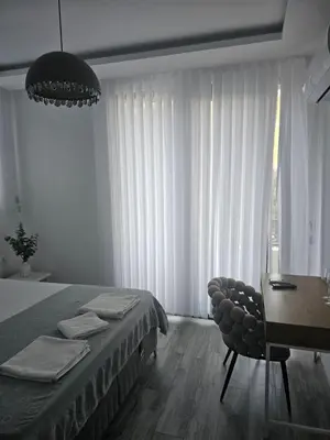 a bedroom with a bed and a table and a chair at La Vida Apartments in Babalonija