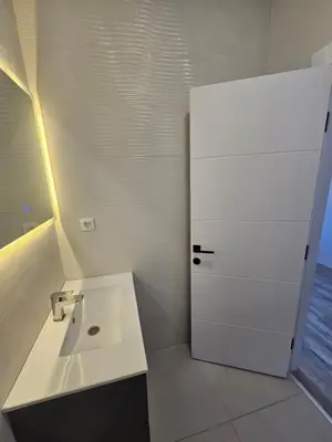 a bathroom with a sink and a white refrigerator at La Vida Apartments in Babalonija