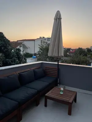 a couch and a table with an umbrella on a roof at Grapefruit Haus in Donji Štoj