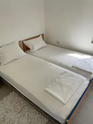 two beds in a room with white sheets and a rug at Grapefruit Haus in Donji Štoj