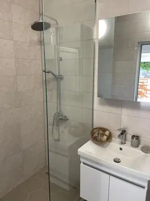 a shower with a glass door next to a sink at Grapefruit Haus in Donji Štoj