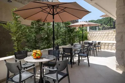a patio with tables and chairs and an umbrella at Adriatic Residence in Budva