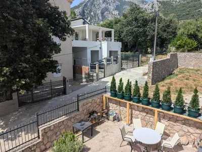 a house with a stone wall and a table and chairs at Villa Seventh Heaven in Sutomore