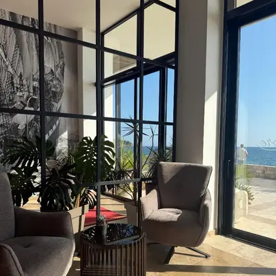 a living room with two chairs and a large window at Hotel Sutomore in Sutomore