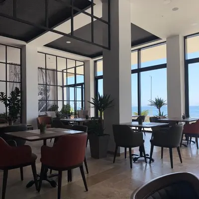 a restaurant with tables and chairs and windows at Hotel Sutomore in Sutomore