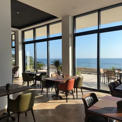 a restaurant with tables and chairs and a view of the ocean at Hotel Sutomore in Sutomore