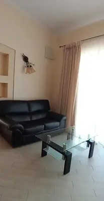 a living room with a black leather couch and a glass table at Villa Delfin 1-2-3-4 in Bar