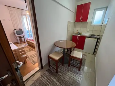 a small kitchen with red cabinets and a table and chairs at Guest House Plima 2 in Budva