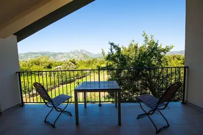 two chairs and a table on a balcony with a view at Happy birds apartment in Virpazar