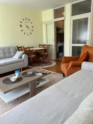 a living room with a table and a clock on the wall at Apartman Bešović Cetinje in Cetinje