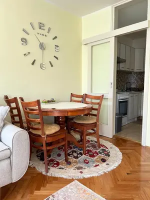 a dining room table with chairs and a clock on the wall at Apartman Bešović Cetinje in Cetinje