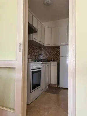 a kitchen with white cabinets and a stove and refrigerator at Apartman Bešović Cetinje in Cetinje