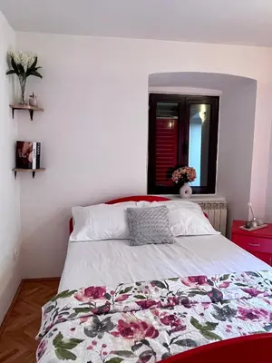 a bedroom with a bed with a floral blanket on it at Apartment Sofija in Kotor