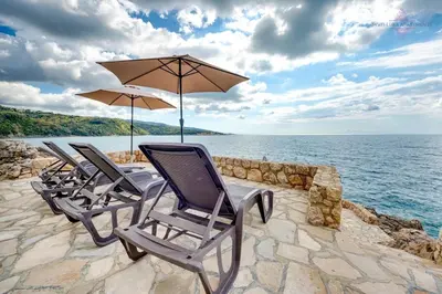 a group of chairs and umbrellas sitting on a stone wall at Sveti Luka private beach in Dobra Voda