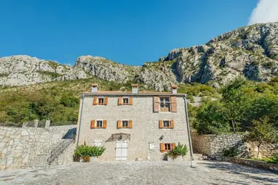 an old stone building with mountains in the background at Villa Sveti Stefan in Budva