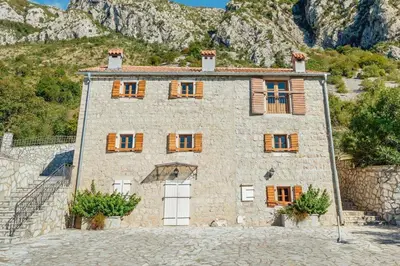 a large stone house with wooden windows on a mountain at Villa Sveti Stefan in Budva