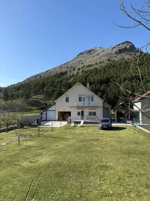 a house with a car parked in front of a mountain at Family house on the mountain - Krstac, Njegusi in Njeguši